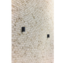 Wand mit rechteckigen Steinen und zwei schwarzen Wandleuchten