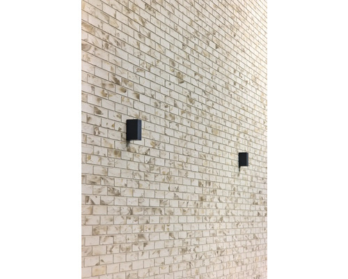Wand mit rechteckigen Steinen und zwei schwarzen Wandleuchten