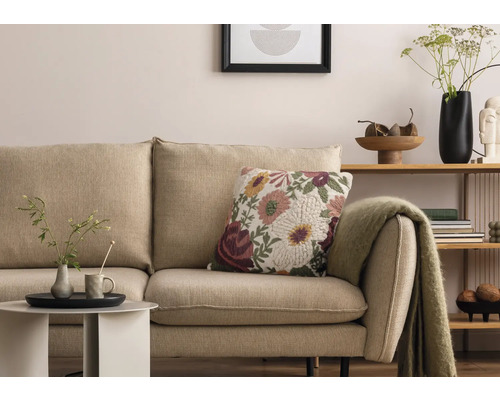 Wohnzimmer-Szene mit beigem Sofa, Blumendekokissen und Beistelltisch