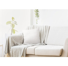 Helles Wohnzimmer mit Sofa, Kissen und Überwurfdecke