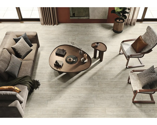 Helles Wohnzimmer mit Sofa, Sesseln, Couchtisch und Holzbodenfliesen in Holzoptik.