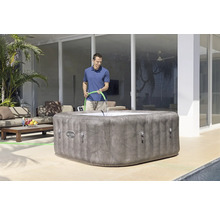 Aufblasbarer Whirlpool im Garten mit einer Person, die ihn mit einem Schlauch befüllt.