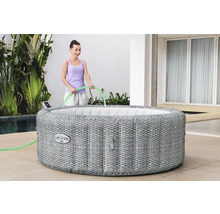 Aufblasbarer Lay-Z-Spa Bali Whirlpool mit geflochtener Optik und einer Person, die ihn mit einem Schlauch befüllt.