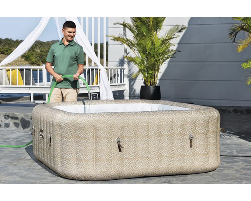 Aufblasbarer Whirlpool mit Mann und Wasserschlauch im Garten