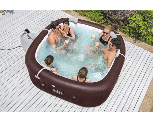 Aufblasbarer Whirlpool mit mehreren Personen im Garten auf einer Holzterrasse