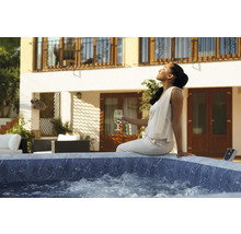 Frau entspannt in einem Outdoor Whirlpool auf der Terrasse eines Hauses.