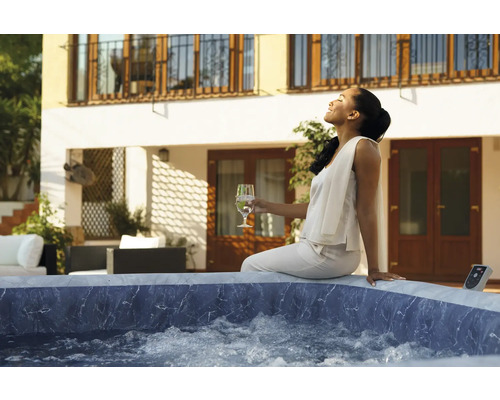 Frau entspannt in einem Outdoor Whirlpool auf der Terrasse eines Hauses.