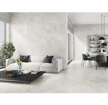 Heller Wohnraum mit Boden- und Wandfliesen in Marmoroptik, Sofa, Tisch und Essbereich