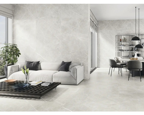Heller Wohnraum mit Boden- und Wandfliesen in Marmoroptik, Sofa, Tisch und Essbereich