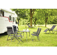 Campingplatzszene mit Wohnwagen, Campingtisch, Campingstühlen und Liegestühlen auf einer Rasenfläche