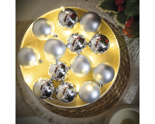 Dekoration mit silberfarbenen Weihnachtskugeln auf einem beleuchteten Tablett