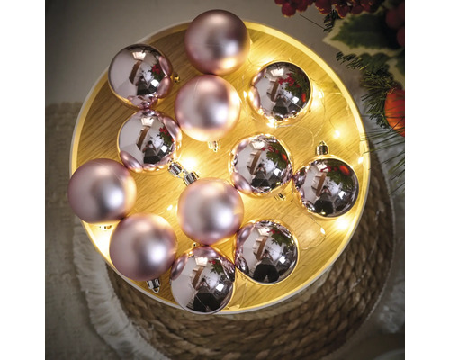 Dekorative rosa Weihnachtskugeln auf einem beleuchteten Tablett.