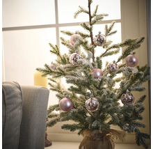 Dekorierter Miniaturweihnachtsbaum mit Kugeln in einem Jutesack