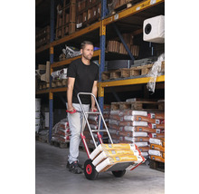Mann transportiert Sackware mit einer Sackkarre in einem Lager.