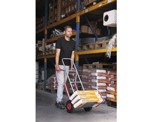 Mann transportiert Sackware mit einer Sackkarre in einem Lager.