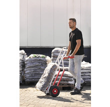 Mann transportiert Sackware mit einer Sackkarre vor einem Lager