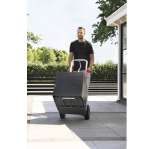 Mann transportiert Box mit einer Sackkarre im Außenbereich.