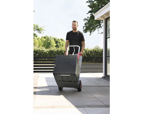 Mann transportiert Box mit einer Sackkarre im Außenbereich.