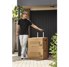 Eine Person zieht zwei Hornbach Umzugskartons mit Trolley-Funktion auf einem gepflasterten Weg.