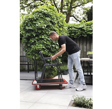Mann transportiert Stühle auf einem Rollbrett im Garten