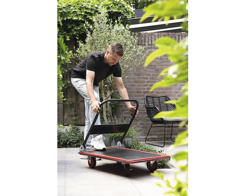 Mann bedient einen Transportroller im Garten.