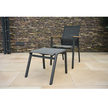 Gartenstuhl mit Fußhocker vor Ziegelwand