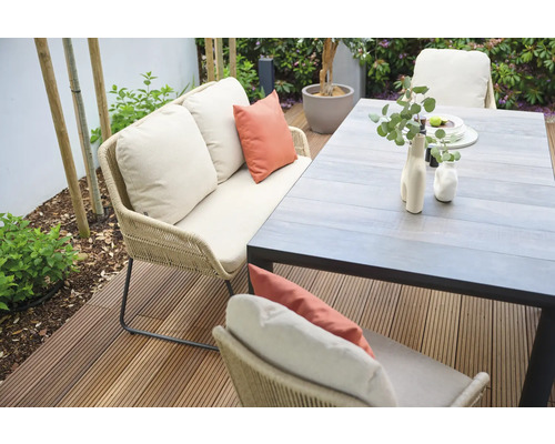 Gartenszene mit Sofa, Kissen und Esstisch auf einer Terrasse