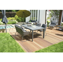 Gartenszene mit Esstisch, Stühlen, Sonnenschirm und Terrasse auf Rasenfläche.
