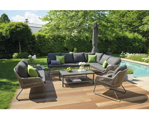 Gartenlounge-Set auf Holzterrasse mit Rasen, Bäumen und Pool im Hintergrund.