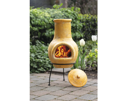 Mexikanischer Ofen mit Feuerstelle, aus Ton gefertigt und mit einem Deckel auf Pflastersteinen im Garten platziert.