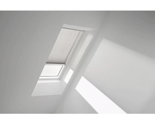 Dachfenster mit teilweise geschlossenem Plissee in einem weißen Raum