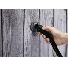 Hand schließt Schlauch an Wandanschluss an