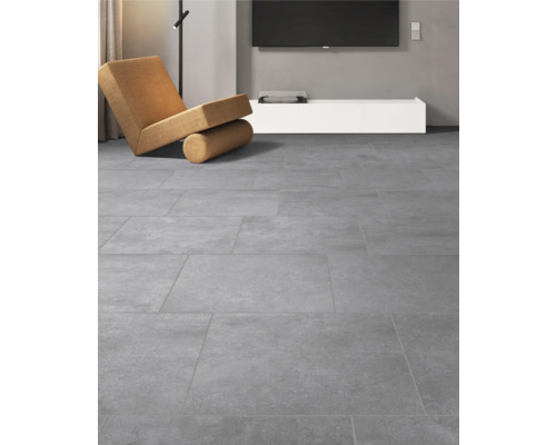 Graue Bodenfliesen in einem Wohnzimmer mit Sessel und Fernseher