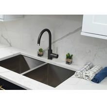 Küchenspüle mit schwarzem Wasserhahn, Arbeitsplatte und zwei kleinen Dekorationen