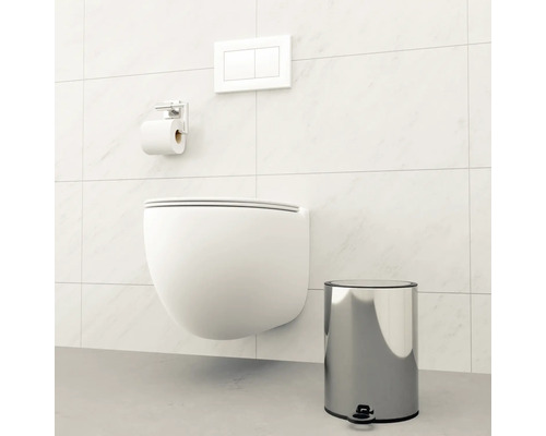 Wandhängendes WC mit Betätigungsplatte, Toilettenpapierhalter und Treteimer in einem Badezimmer.