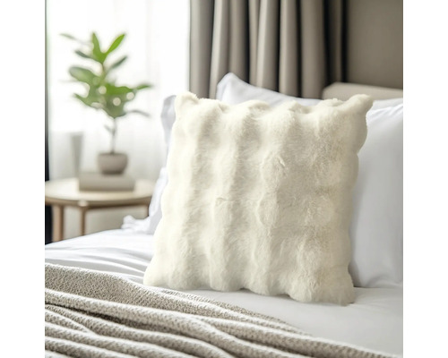 Dekoratives Fellkissen auf einem Bett im Schlafzimmer.