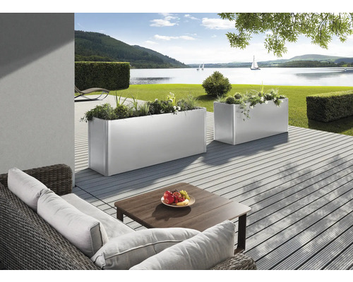 Szene mit zwei bepflanzten, rechteckigen Pflanzkästen auf einer Terrasse mit Blick auf einen See