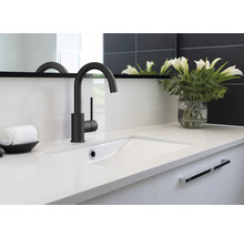 Waschbecken mit Armatur, Handtuch und Blumenvase im Badezimmer.
