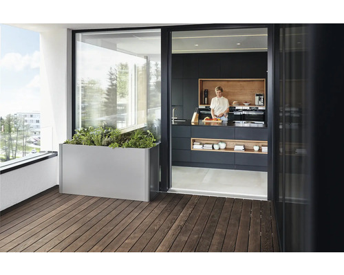 Balkonszene mit einem Pflanzkasten aus Metall und einer Frau in einer modernen Küche