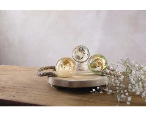 Drei dekorative Kugeln mit Pflanzenmotiven auf einem Holztablett