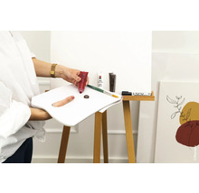 Szene mit Acrylfarben, Pinsel, Farbpalette und Leinwand auf einer Staffelei.