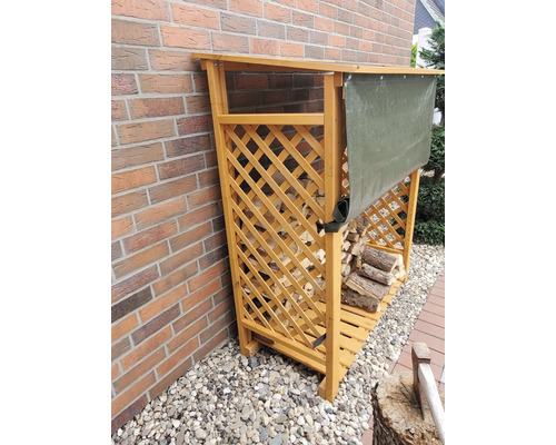 Holzlager aus Holz mit Abdeckung vor einer Ziegelwand