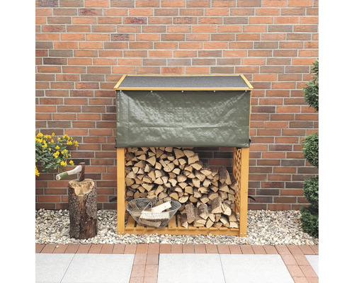 Holzregal mit Plane, gefüllt mit Holz vor einer Backsteinmauer