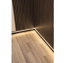 Zimmer-Ecke mit Holzpaneelwand, Sockelleiste mit LED-Streifen und Laminatboden