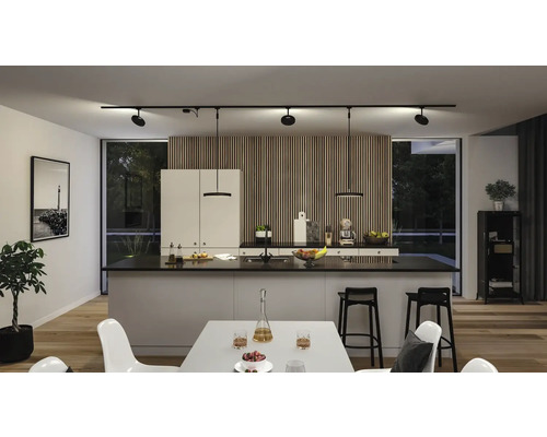 Helle Küche mit Kücheninsel, schwarzen Barhockern und Schienenstrahler an der Decke.