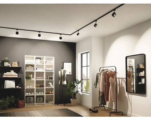 Ankleidezimmer mit Regalen, Kleiderständer, Spiegel und schwarzem Schienensystem mit Strahlern