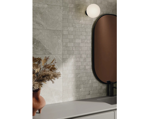 Wandgestaltung mit Fliesen in Steinoptik und Mosaikfliesen, kombiniert mit einem Spiegel und einer Lampe