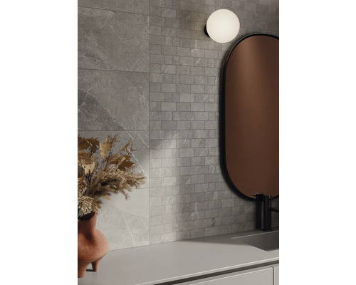 Badezimmer mit grauen Wandfliesen in Steinoptik, Spiegel und Lampe