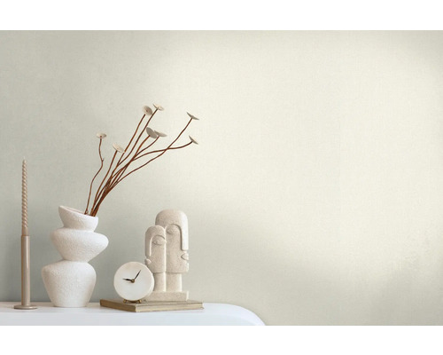 Dekorative Szene mit einer Vase, Zweigen, einer Kerze, einer Uhr und einer Skulptur auf einem Tisch.