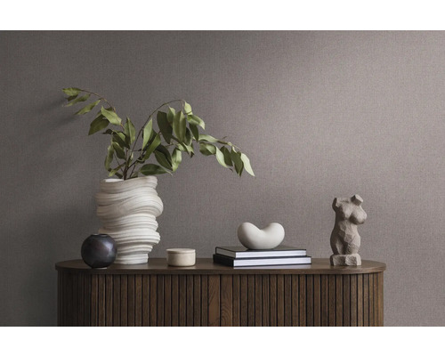 Dekoratives Arrangement auf einem Holzschrank mit Vase, Büchern und Skulptur